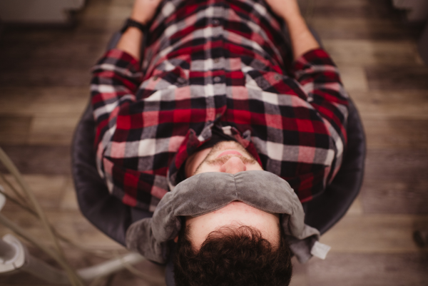 a man laying back in a dental chair with weighted bean bags covering his eyes in a relaxed state